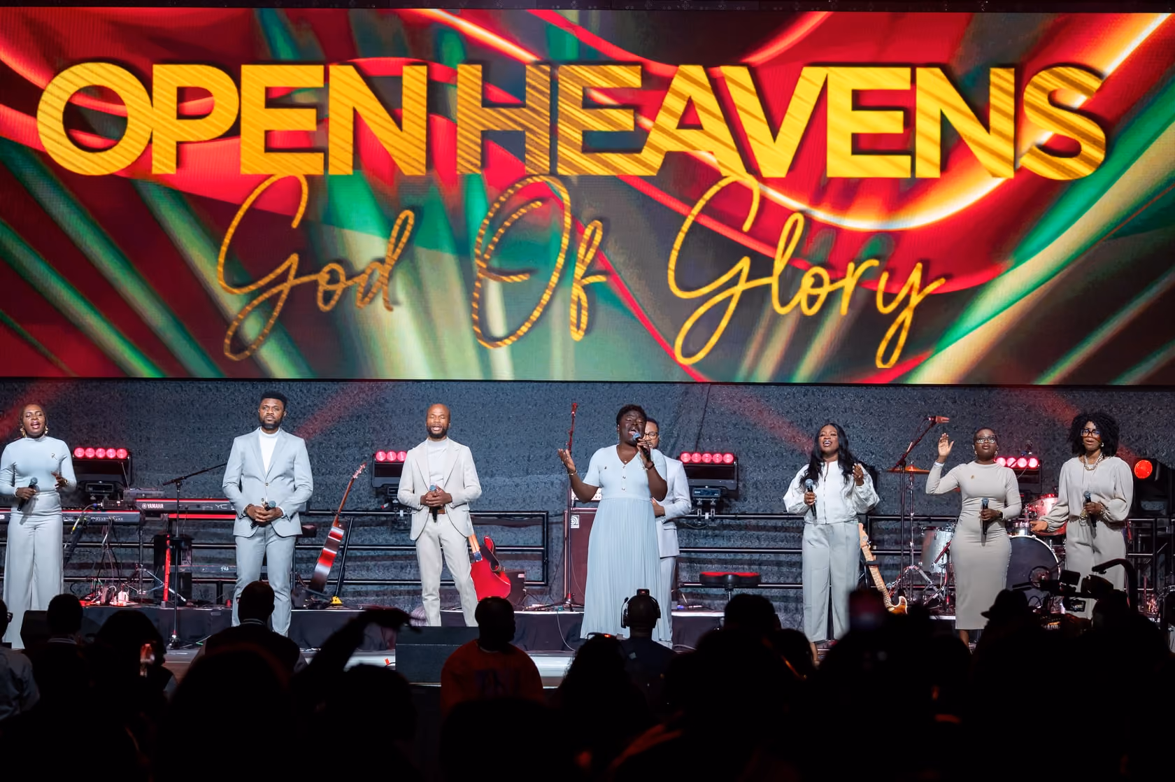 The Open Heavens worship team on stage in front of a God of Glory backdrop.