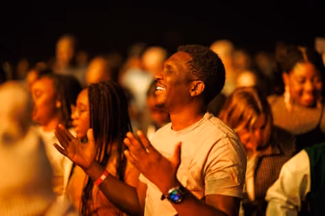 A man in the crowd clapping and laughing.