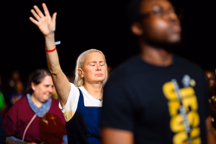 A woman with one hand raised in worship.
