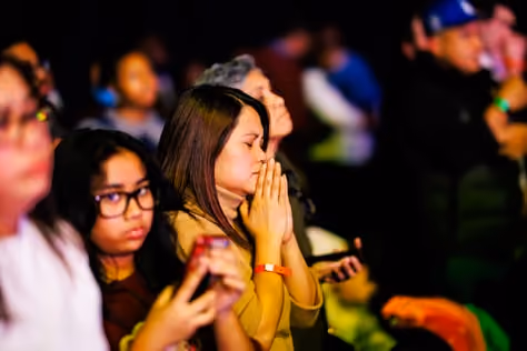 Two women praying with their hands together.