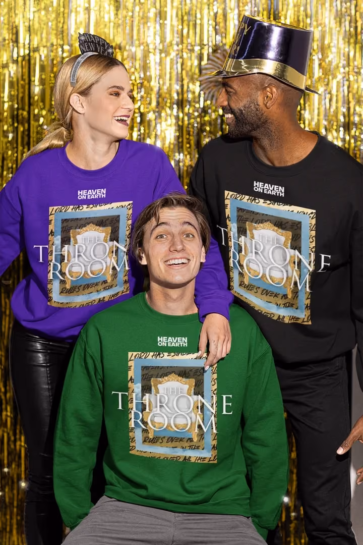Three people wearing Open Heavens Throne Room sweatshirts in front of a gold streamer backdrop.